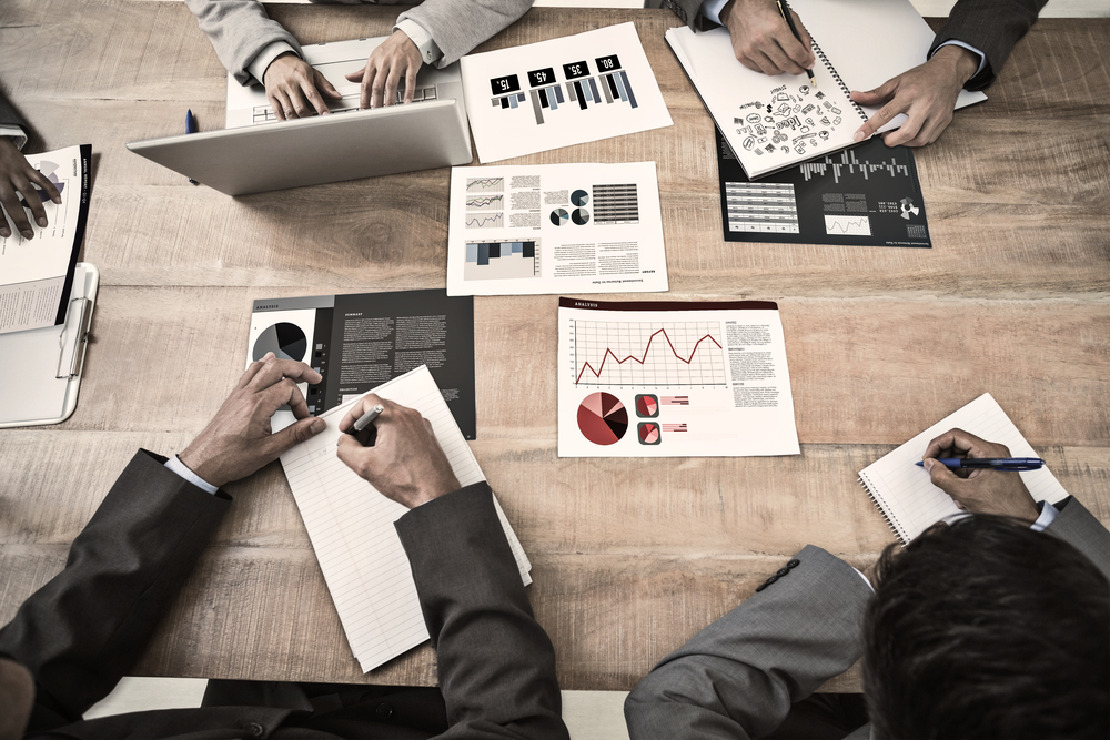 Birds eye view of table with data security experts working on laptops and papers, to illustrate our guest blog post on microsharding: enhanced data security in an insecure world